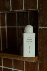 White 250ml Beauty Engine Sweet Almond and Manuka Honey shower oil bottle in a tiled shower niche.