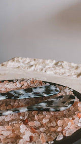 Saltist acrylic spoon and butter knife set in a black and white tortoiseshell pattern resting on pink salt crystals.