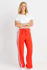 Woman wearing red Jamie joggers with white side stripes featuring a red heart pattern and a drawstring waistband.