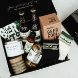 Gift box with beer bottles, snacks, and a beer cooler labeled 'rad dad' on a white surface.