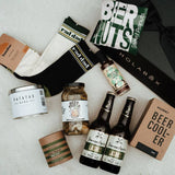 Collection of beer-themed items including bottles, a beer cooler, and snacks on a light surface.