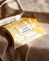 Packaged product with 'Golden Glow A Little Something' branding on a textured fabric background