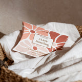 Two facial mask packages labeled 'A Little Something' on a textured surface with a neutral background.