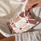 Hand holding a box labeled 'A Little Something' with floral design