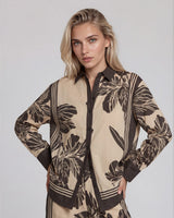 Woman wearing a beige and brown patterned outfit on a plain background