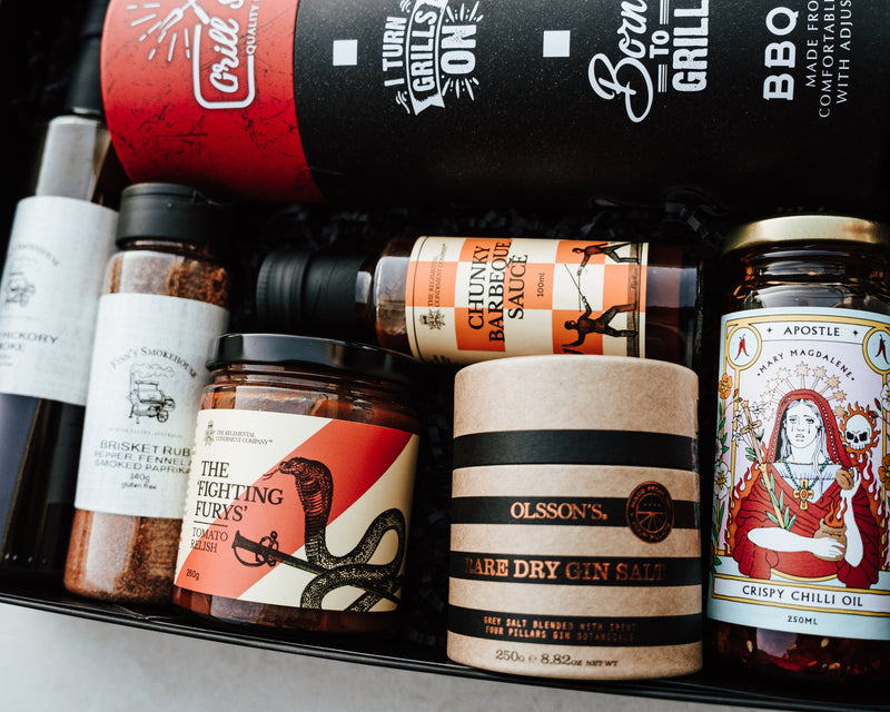Assorted food products including spices, sauces, and a bottle of gin in a box.