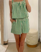 Woman taking a mirror selfie wearing a green and white striped dress in a store.
