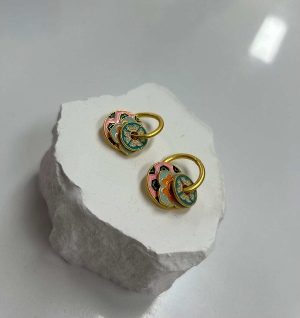 Colorful Mica Hoop Earrings with multicolor enamel design on gold hoops displayed on white stone pedestal