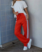 Woman wearing red Jamie joggers with white side stripes featuring red heart patterns and a drawstring waistband.