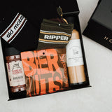 Gift box with various items including a bottle of beer, a can of beer, and a jar of peanut butter.