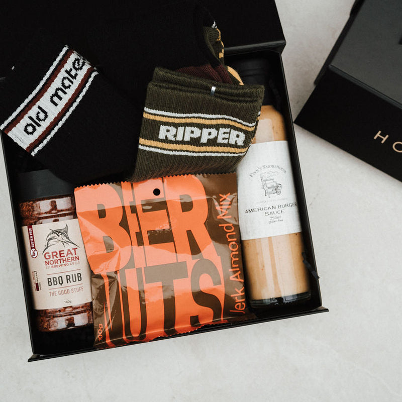 Gift box with various items including a bottle of beer, a can of beer, and a jar of peanut butter.