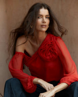 Red one-shoulder viscose top featuring a sculptural floral appliqué and voluminous long sleeves.