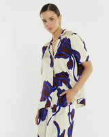 Jade satin shirt with a camp collar, brown mock horn buttons, and a bold blue and dark brown floral print.