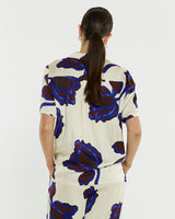 Back view of a cream satin shirt with a blue and brown floral print, featuring a camp collar and relaxed fit.