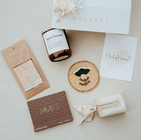 Collection of wedding-related items including a candle, card, and boxes on a light surface with 'HOLABOX' branding.