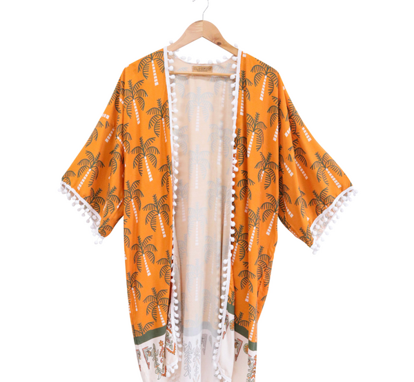 Orange kimono with palm tree pattern on a hanger against a white background