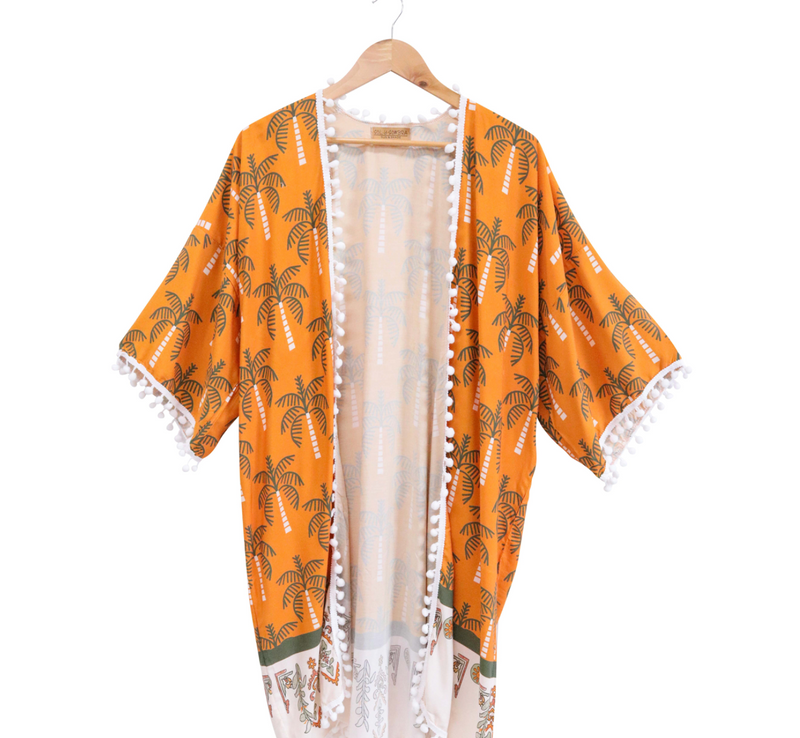 Orange kimono with palm tree pattern on a hanger against a white background