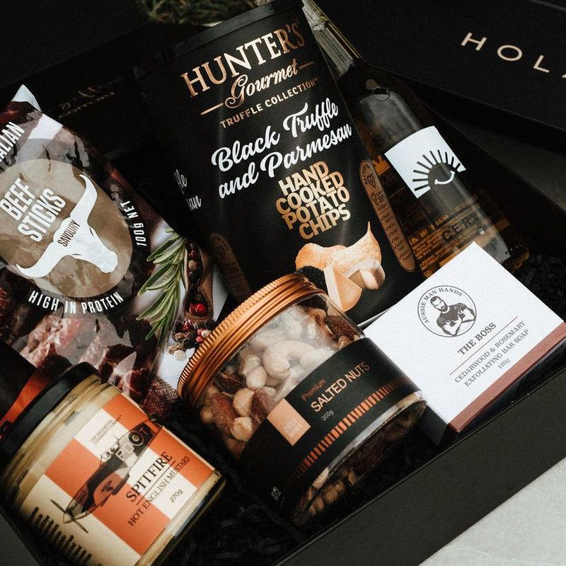 Assorted gourmet snacks in a black gift box with visible brand names.