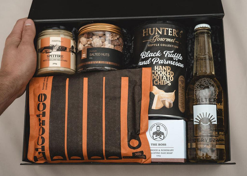 Gift set with gourmet snacks, beer, and a blanket in a black box.
