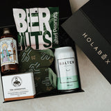 Gift box with various items including a can of Balter XPA, a bottle of hot sauce, and a bar of soap, branded 'HOLABOX'.