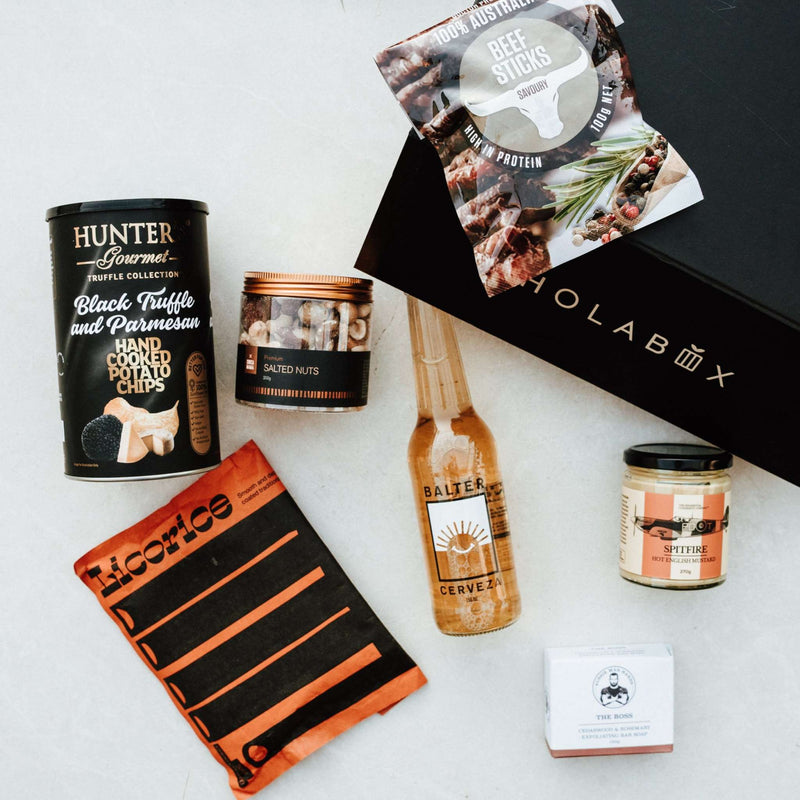 Collection of gourmet food items and a black box labeled 'HOLABOX' on a light gray background.