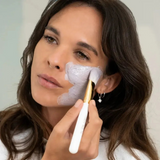 House of Holabox model applying Stray Willow purple berry antioxidant facial mask with a brush to her cheek