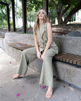 Sage green belted vest with wide notched lapels and matching wide-leg trousers, worn by a woman sitting on a bench.
