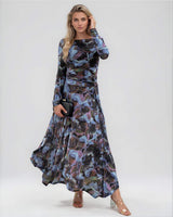 Model wearing a long-sleeved blue blurred floral mesh dress with a boat neckline and gathered skirt detail.