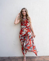 Woman wearing a red floral print Anella tank dress with a shirred bodice and relaxed midi-length skirt.