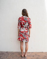 Woman wearing a red and white floral print linen-blend wrap dress with short sleeves, viewed from the back.