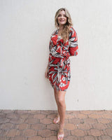 Woman wearing a red and white floral print linen-blend wrap dress with a tie waist and short sleeves.