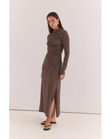 Model wearing a brown long-sleeved midi dress with white polka dots, high neckline, and side-ruched detailing.
