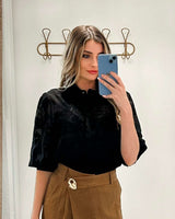 Black Aurora shirt with crane embroidery, puffy sleeves, and wide cuffs, worn with a brown skirt.