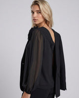 Black one-shoulder viscose top featuring a sculptural floral appliqué, gathered neckline, and voluminous long sleeve.