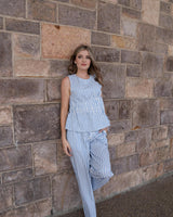 Woman wearing blue and white striped seersucker wide-leg pants with an elastic waist and matching sleeveless top.