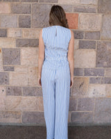 Woman wearing blue and white striped seersucker wide-leg pants with an elasticated waist against a stone wall.