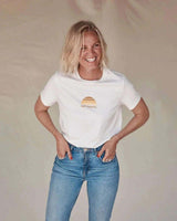 Woman wearing a natural organic cotton tee with a tonal sun print and Rad Mama text in a classic crew neck style.