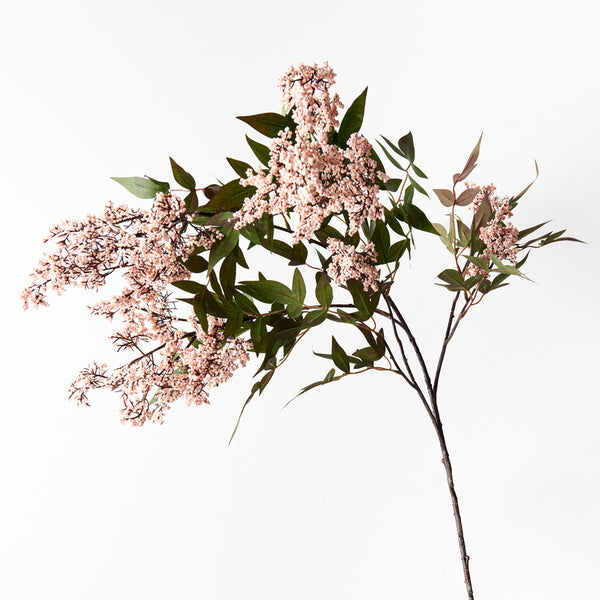 Artificial flower branch with pink flowers and green leaves on a white background