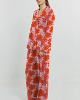 Soft stretch jersey pyjama set in pink with a red floral print, featuring a button-through shirt and relaxed long pants.