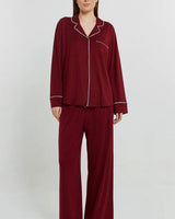 Women wearing a plum long-sleeve button-down pajama set in soft stretch jersey with white contrast piping.