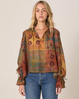 Bohemian long-sleeve top in a multi-colored floral print with a front neck tie, drop shoulders, and frill hem cuffs.