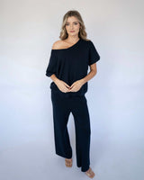 Model wearing a navy blue Bonnie knit top with an off-the-shoulder neckline and matching wide-leg knit trousers.
