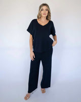 Woman wearing a navy blue cotton viscose V-neck knit top with matching wide-leg trousers.