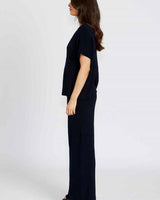Side view of a woman wearing comfortable, navy blue cotton viscose Bonnie pants with a matching short-sleeve top.