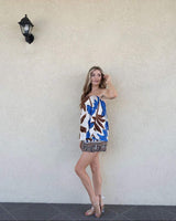 Woman wearing a strapless cotton top and matching shorts set with a blue and brown floral print against a beige wall.
