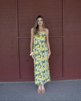 Woman wearing a yellow and green lemon-print cotton maxi dress with white lace trim details and spaghetti straps.