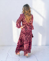 Woman wearing a vibrant cerise safari print polyester maxi dress with long sleeves and a flowing silhouette.