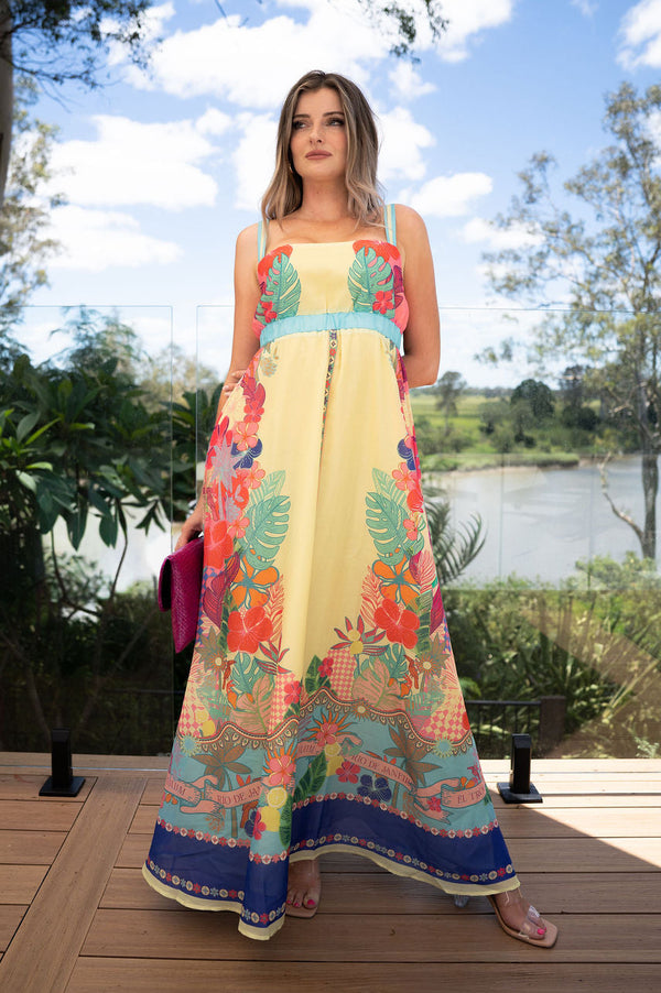 Woman in a colorful dress standing on a wooden deck with a scenic background