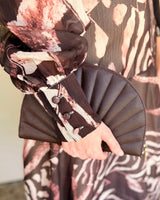 Chantelle maxi dress in chocolate brown abstract print with long cuffed sleeves, paired with a pleated fan clutch.
