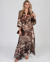 Model wearing a chocolate brown, long-sleeved maxi dress with a flowing skirt and abstract animal print pattern.